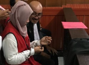 Ayuk alias Puspita, terdakwa perdagangan orang (berjilbab) tengah berbincang dengan seseorang usai menjalani sidang di PN Surabaya.