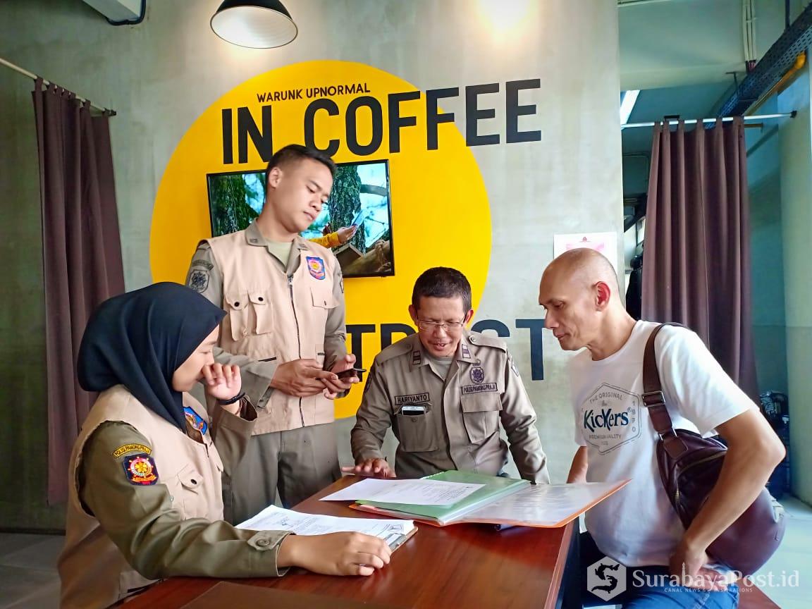 Petugas Satpol PP Pemkot Malang bidang pengawasan, Hariyanto (dua dari kanan) saat memeriksa kelengkapan perizinan cafe Warunk Upnormal dan ditemui oleh Heri Purnomo (kanan) selaku pemilik usaha.
