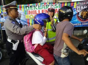 Kanit Dikyasa Satlantas Polres Malang Kota Iptu Muhammad Syakhu mberi helm pada siswa yang takamu pakai helm.