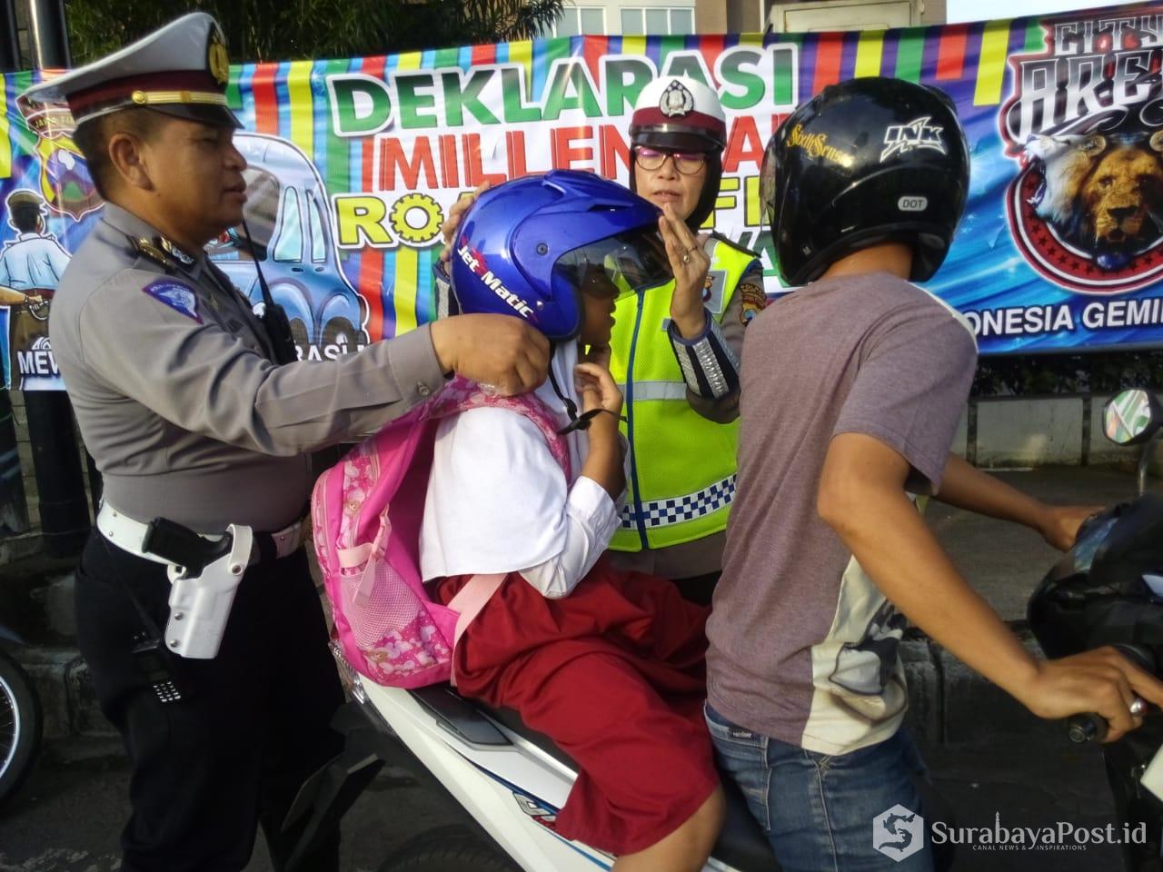 Kanit Dikyasa Satlantas Polres Malang Kota Iptu Muhammad Syakhu mberi helm pada siswa yang takamu pakai helm.