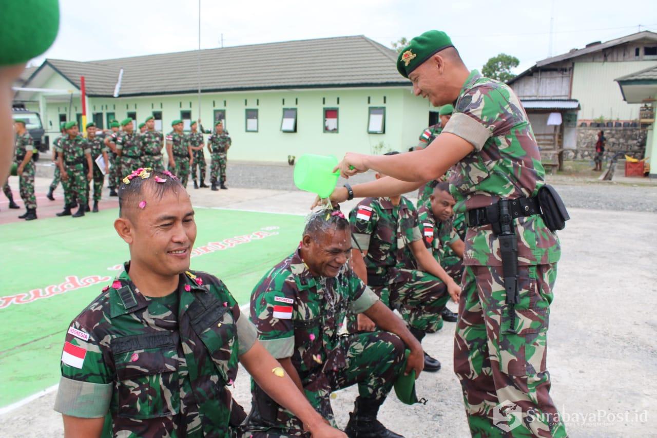 Komandan Satgas Pamtas RI-RDTL Sektor Barat Yonif Mekanis 741/Garuda Nusantara Mayor Inf Hendra Saputra melakukan upacara siram air bunga pada kepala anggota yang naik pangkat.