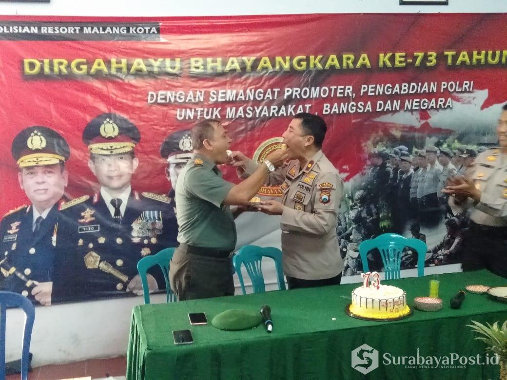 Danramil Klojen, Kapten Inf Sunarko saat memberikan kado istimewa berupa kue tar sekaligus menyuapi  Kapolsek Klojen, Kompol Budi Haryanto
