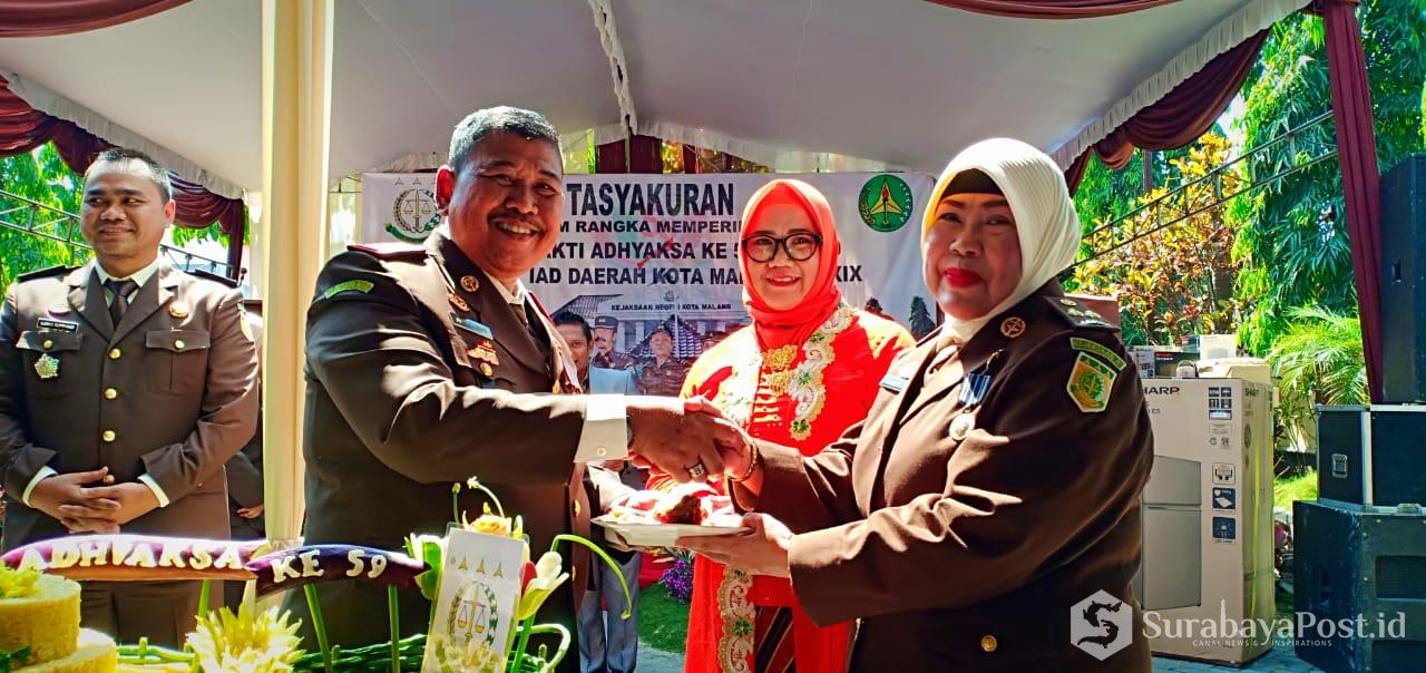 Kajari Kota Malang, Amran Lakoni didampingi istri saat memberikan potongan tumpeng kepada jaksa paling senior Sudarwati di acara tasyakuran Hari Bhakti Adhyaksa (HBA) ke 59 di Kejari Kota Malang.