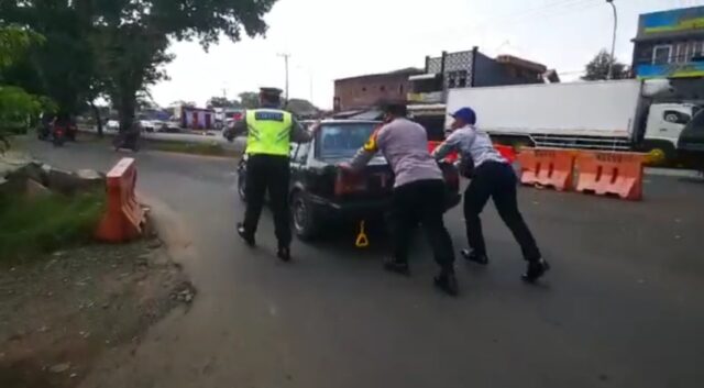 Aksi mulia yang dilakukan dua personel Polresta Malang Kota dan Dishub saat membantu mendorong mobil mogok milik salah satu pemudik (ist)