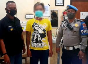 Tersangka (kaos kuning) diapit Petugas Polres Batu