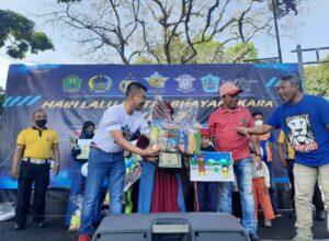 Kasatlantas Polresta Malang Kota, Kompol Yoppy Anggi Khrisna ?kaos putih) memberikan hadiah kepada pemenang (ist)