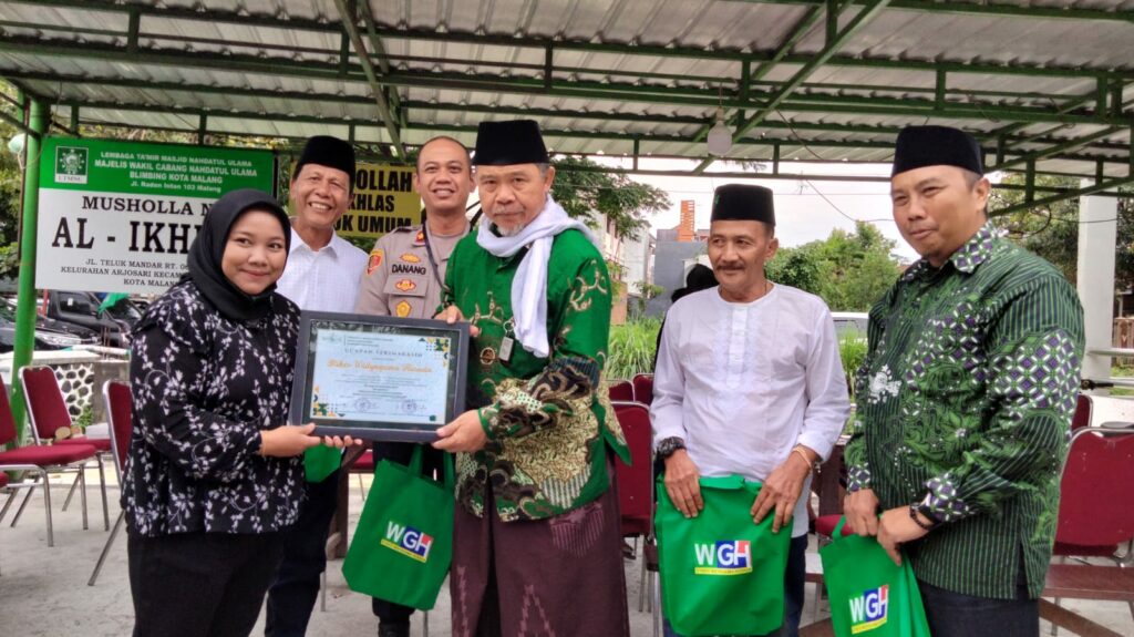 Ketua Rois Syuriah MWC NU Blimbing, KH. Syaifudin Zuhri menerima piagam penghargaan dari salah satu Sponsorship pada pelaksanaan khitanan massal. (ft.cholil)