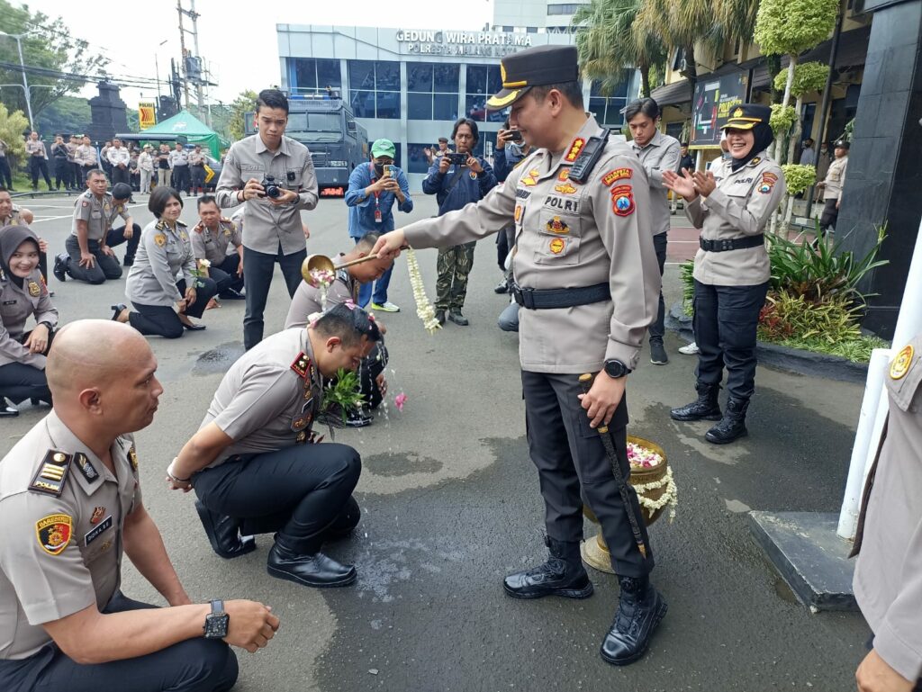 Kapolresta Malang Kota Kombes Pol Budi Hermanto mengguyur kepala Kasat Reskrim Kompol Bayu Febrianto Prayoga dengan siraman air bunga. (istimewa).