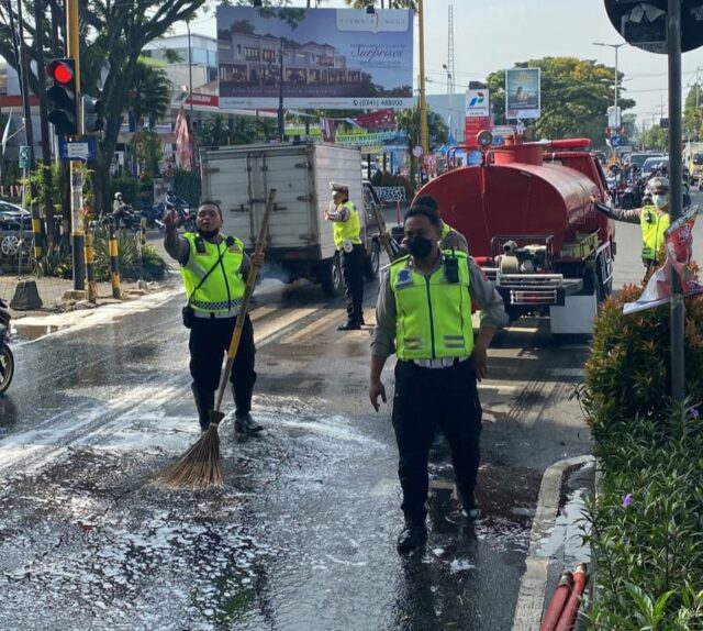 Anggota Satlantas Polresta Malang Kota dan PMK bersihkan tumpahan solar di Jalan. (Istimewa)