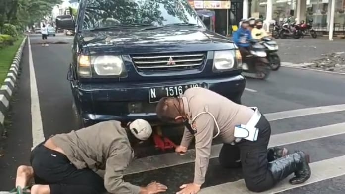 SUNGGUH MULIA : AKP Syaikhu, Kanit Turjawali Polresta Malang Kota membantu mendongkrak mobil yang mengalami kerusakan. (istimewa)