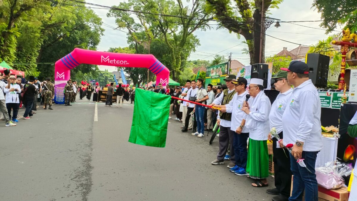 Walikota Malang, H Sutiaji (mengangkat bendera) memberangkatkan peserta gerak jalan sehat kreatif dalam peringatan Satu Abad Nahdlatul Ulama