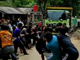 Masyarakat bersatu TNI gotong royong menarik truk tronton menggunakan tali tambang