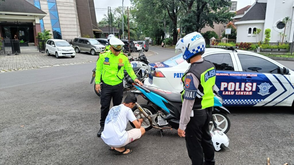Pengendara yang terjaring razia, melepas knalpot brong disaksikan anggota Satlantas Polresta Malang Kota