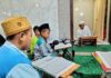 Ustad Suyanto menyimak bacaan Alquran dari anak didiknya di TPQ Az Zahro saat Tadarus di Masjid Babul Hidayah