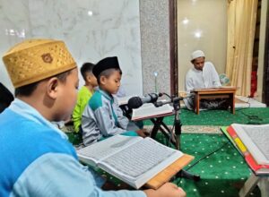Ustad Suyanto menyimak bacaan Alquran dari anak didiknya di TPQ Az Zahro saat Tadarus di Masjid Babul Hidayah