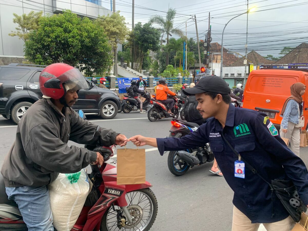 Salah satu pegawai Perumdam Among Tirto membagikan takjil kepada pengendara roda dua