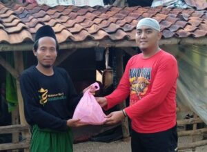Hengki Giantoro (kanan) anggota Komunitas Genk Trail Tua (GTT) Pamekasan menyerahkan bantuan kepada warga di Desa Rangperang dan Rekkerrek. (istimewa)