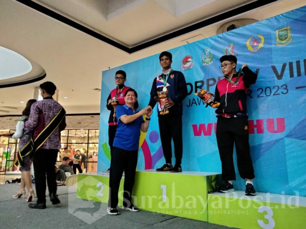 Ketua Umum Pengcab Wushu Kota Malang, Sutjipto Gunawan mengalungkan medali emas pada atlet Wushu Kota Malang di Porprov VIII Jatim (ft.cholil)