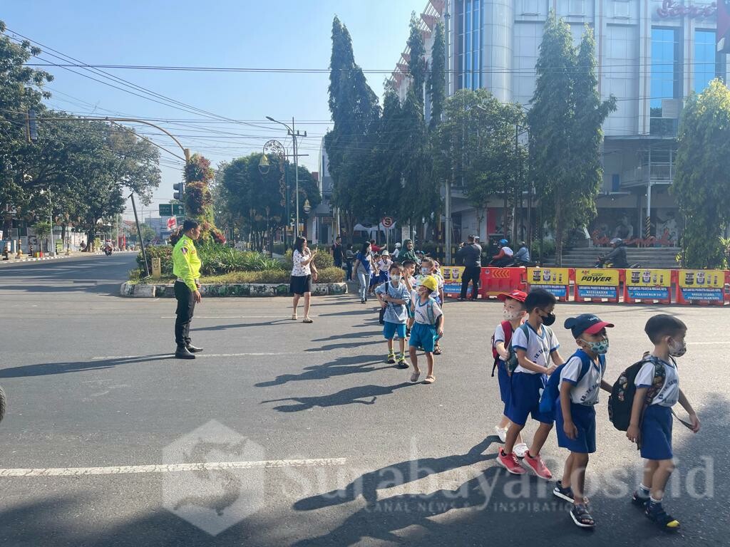 SIMPATIK: Anggota Satlantas Polresta Malang Kota membantu siswa TK beserta para guru menyeberang jalan (ist)