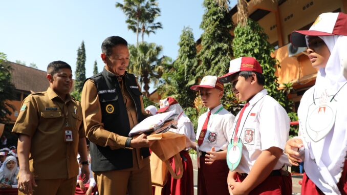 Pj. Wali Kota Malang, Wahyu Hidayat didampingi Kepala Disdikbud, Suwarjana menyerahkan bantuan seragam sekolah secara simbolis, Senin 15 Juli 2024. (Sumber Prokompim)