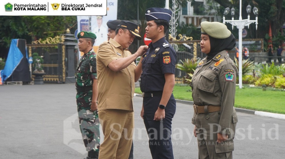 Pj, Walikota Malang, Iwan Kurniawan, ST, MM menyematkan pin Sigap Pilkada Damai dan Gempur Rokok Ilegal. (Sumber Prokompim)