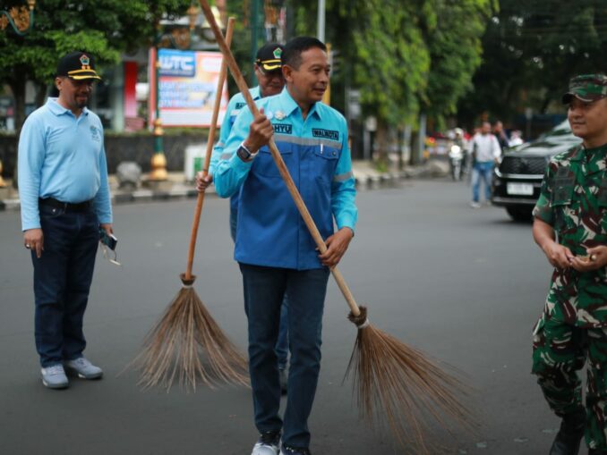 Wali Kota Malang, Dr. Ir. Wahyu Hidayat, M.M., turut turun tangan membersihkan trotoar. Nampak ia memegang sikat dan mulai menggosok trotoar yang sebelumnya terlihat kusam dan berdebu. (Sumber Prokompim).