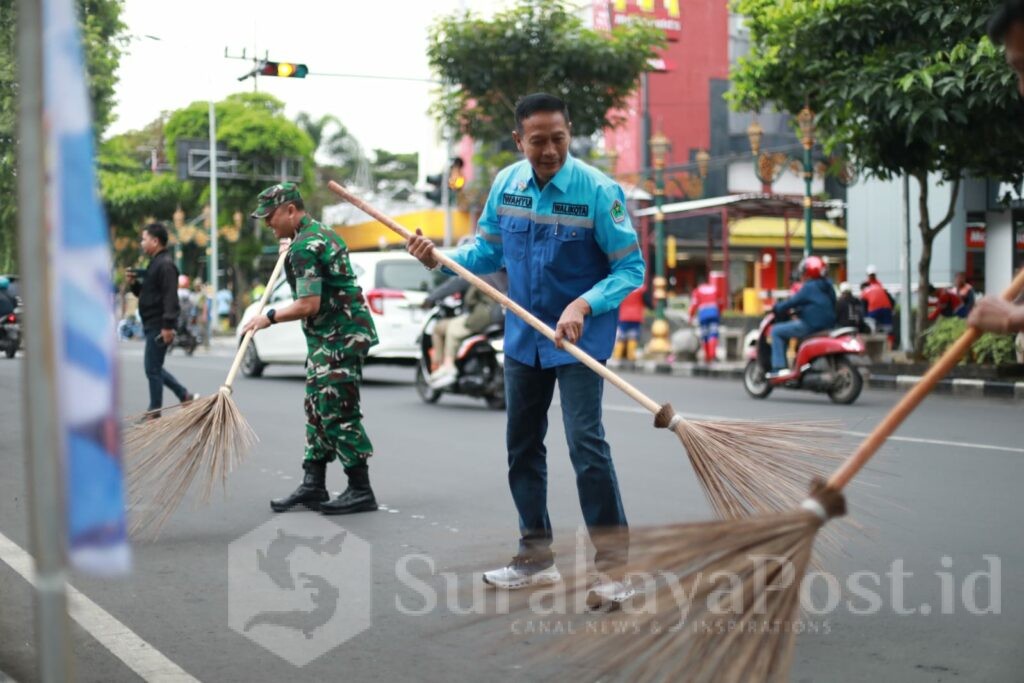 Wali Kota Malang, Dr. Ir. Wahyu Hidayat, M.M., turut turun tangan membersihkan trotoar. Nampak ia memegang sikat dan mulai menggosok trotoar yang sebelumnya terlihat kusam dan berdebu. (Sumber Prokompim).