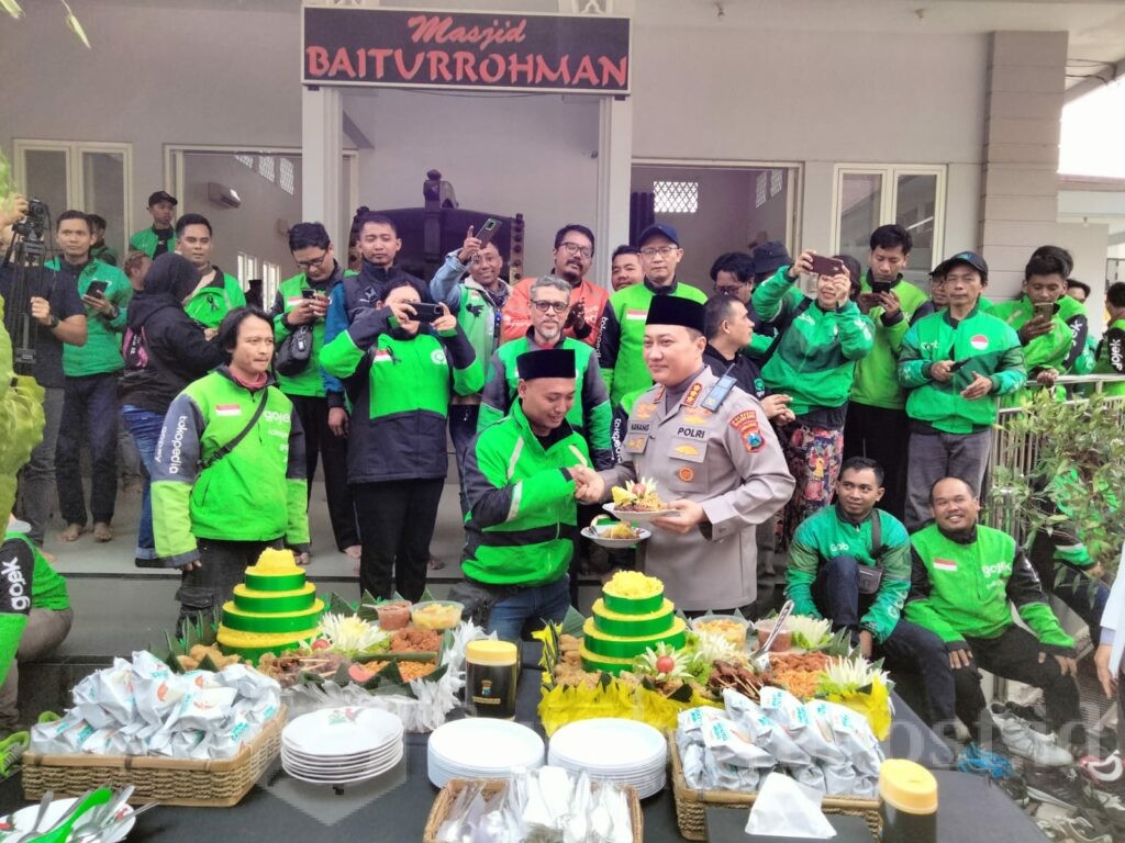 KEBERSAMAAN: Kapolresta Malang Kota, Kombes Pol Nanang Haryono memberikan potongan nasi tumpeng kepada perwakilan driver ojol