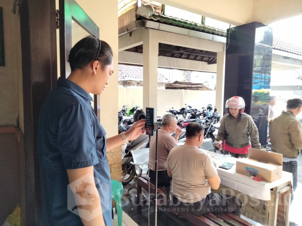 Petugas Polsek Kedungkandang tampak live TikTok dalam gelaran beras murah yang disambut antusias warga.