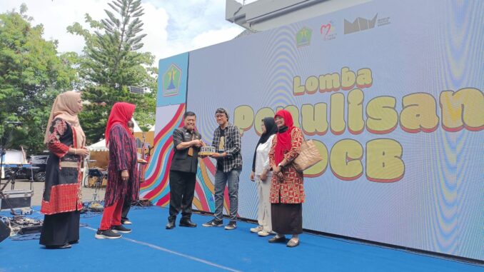 Kepala Disdikbud Kota Malang, Suwarjana, SE, MM, menyerahkan trophy dan piagam penghargaan kepada salah satu kategori pemenang lomba di Museum Mpu Purwa, Kamis (6/11/2025).