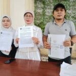 MENANG: Helly, SH, MH, kuasa hukum Tatik Suwartiatun (tengah) dan Sasa (putri Tatik) menunjukkan hasil putusan PN Bangil yang memenangkan permohonan praperadilan, Jumat (28/11/2025).