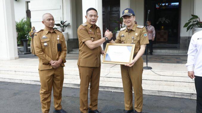 Wali Kota Malang, Dr. Ir. Wahyu Hidayat, MM, menyerahkan piagam penghargaan dari Gubernur Jawa Timur, Khofifah Indar Parawansa, kepada Dinas Kesehatan Kota Malang. (Sumber Prokompim).