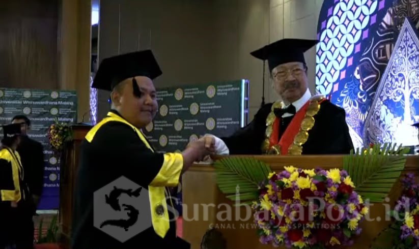 Rektor Unidha Malang, Prof. Dr. H. Suko Wiyono, S.H., M.H., menyematkan toga ke salah satu wisudawan.